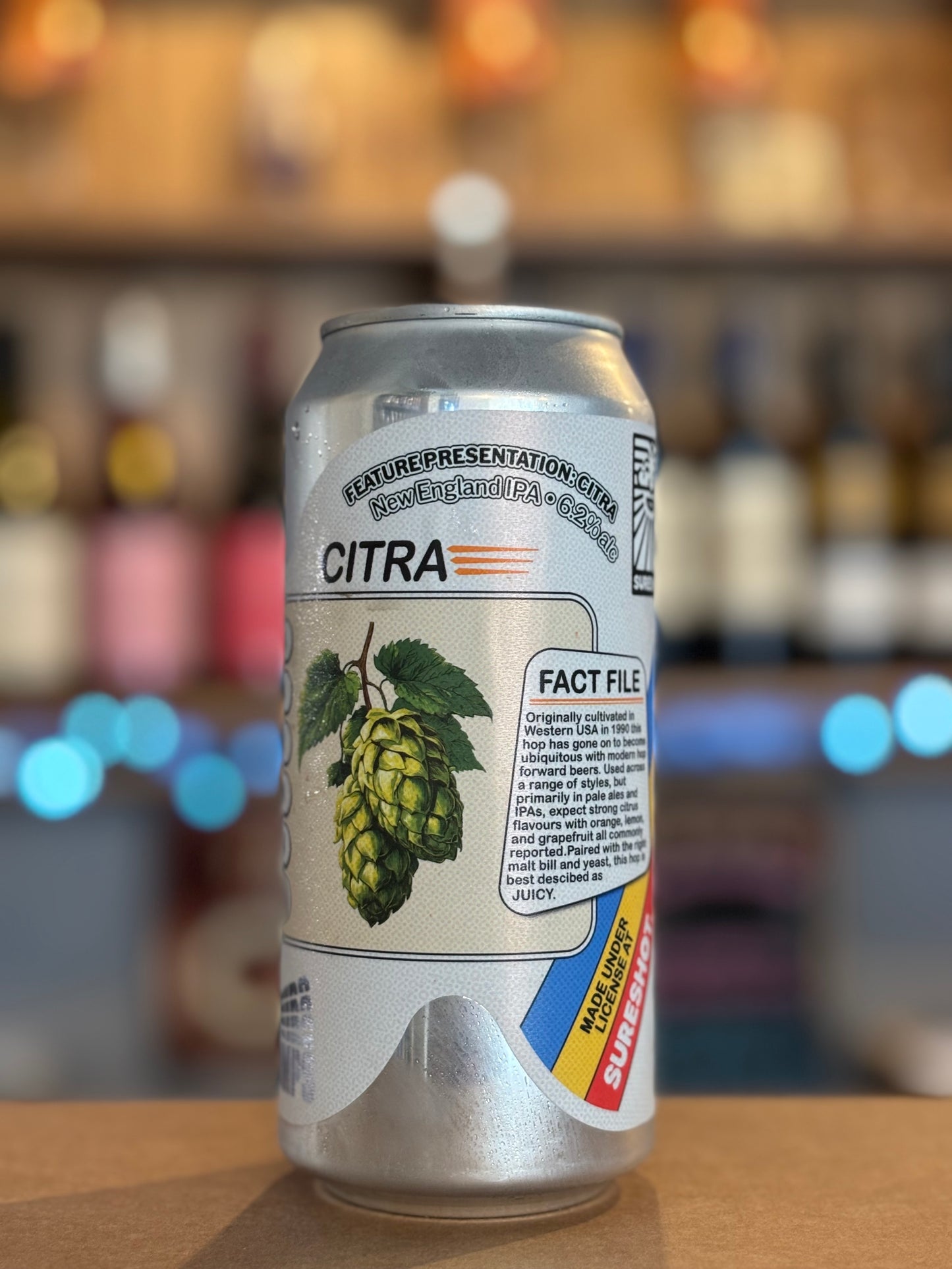 Citra beer can with hop illustration on a blurred bar background