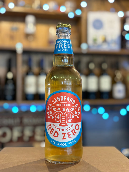Bottle of Sandford Red Zero alcohol-free cider on a bar counter with blurred shelves in the background.