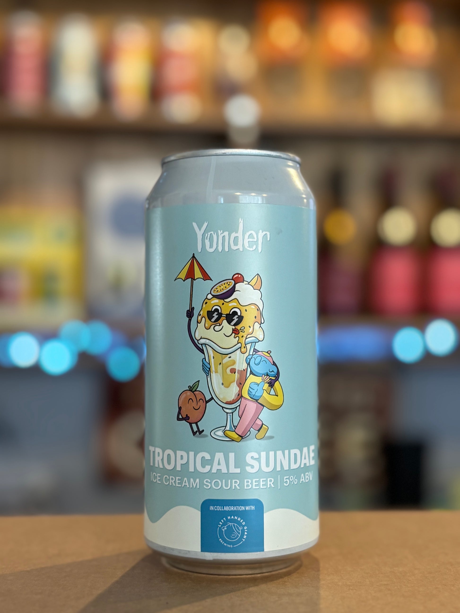 Yonder Tropical Sundae beer can on a bar counter with a blurred bar background