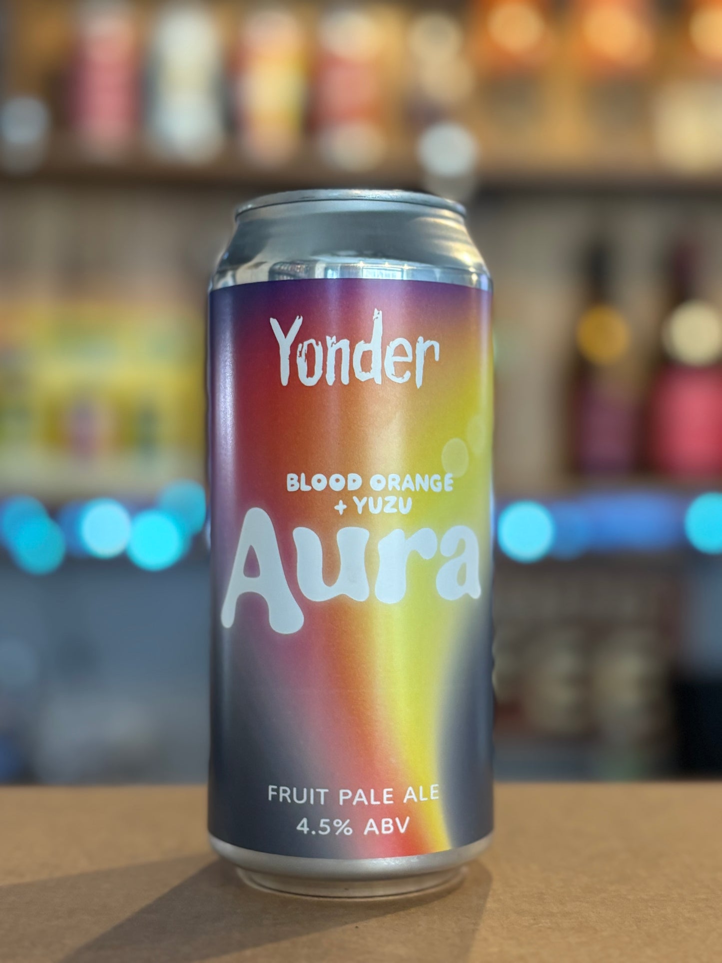 Yonder Aura Blood Orange + Yuzu fruit pale ale can on a bar counter with blurred background