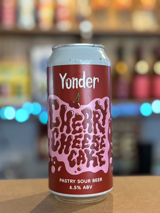 Yonder Cherry Cheesecake beer can on a bar counter with a blurred bar background